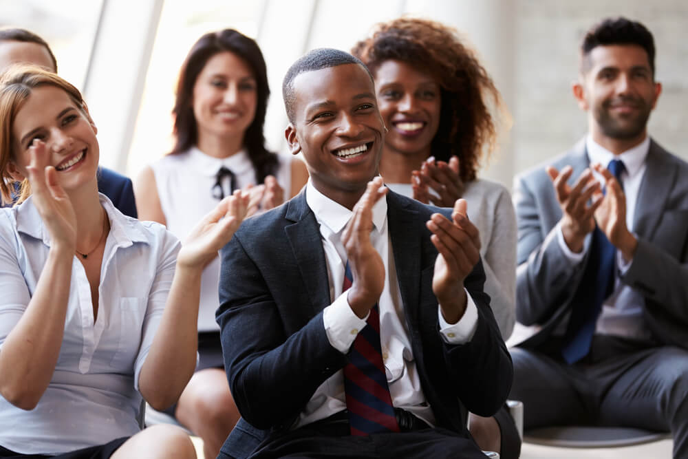 colaboradores de empresa aplaudindo e sorridentes