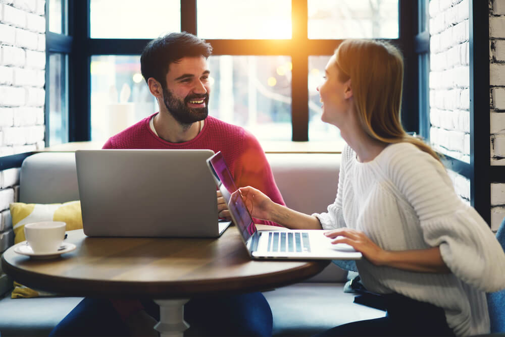 homem e mulher em mesa de cafeteria conversando simbolizando o trabalho em equipe na redaçao publicitaria