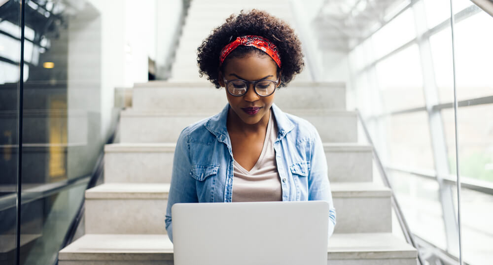 mulher focada em laptop escrevendo redaçao publicitaria