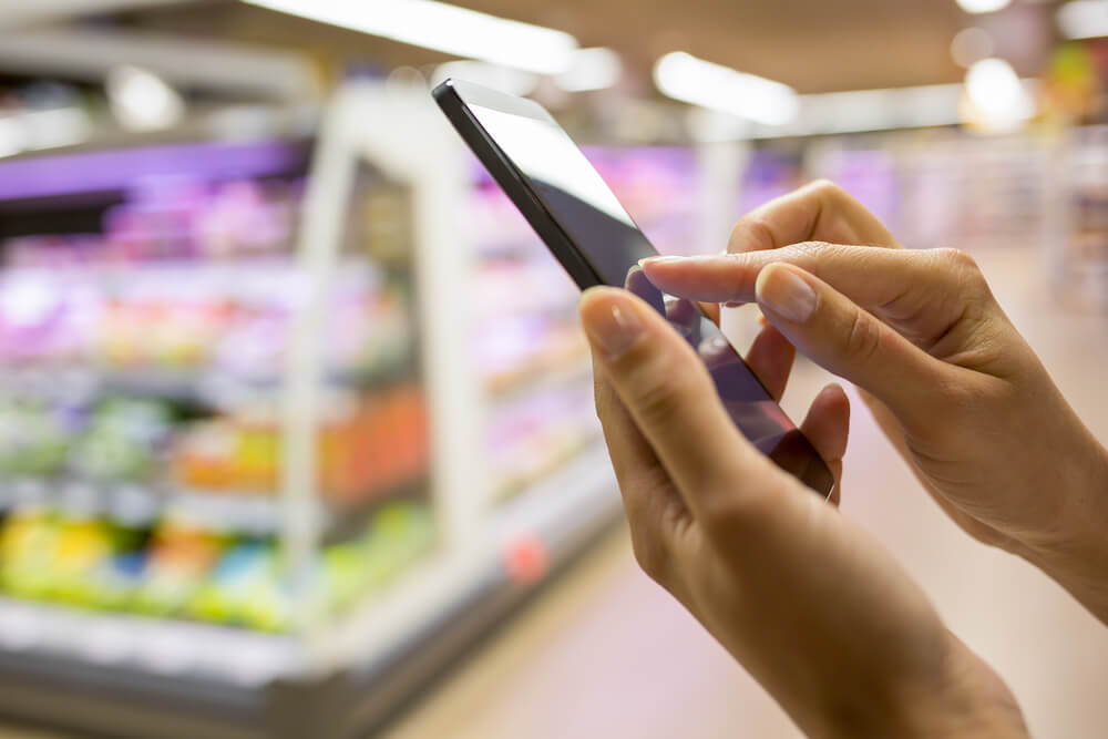 pessoa acessando smartphone em mercado ao fundo