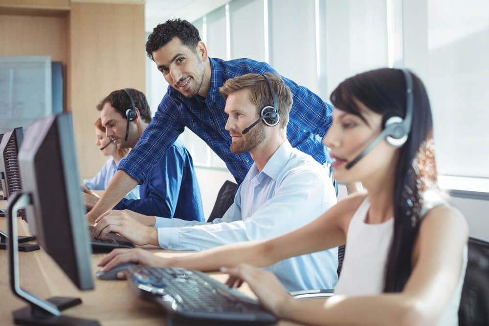 profissional em vendas por telefone em meio a area de trabalho treinando equipe 