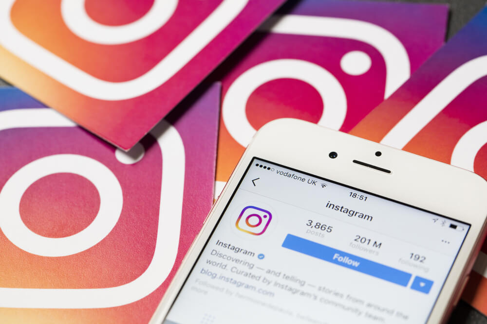 smartpgone em mesa com simbolos do aplicativo instagram ao fundo e opçao de download de instagram em tela